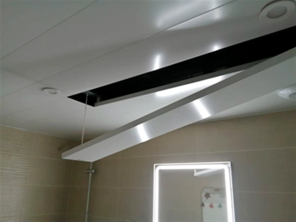 Puerta de registro abierta en un techo de aluminio DILUVID de un baño