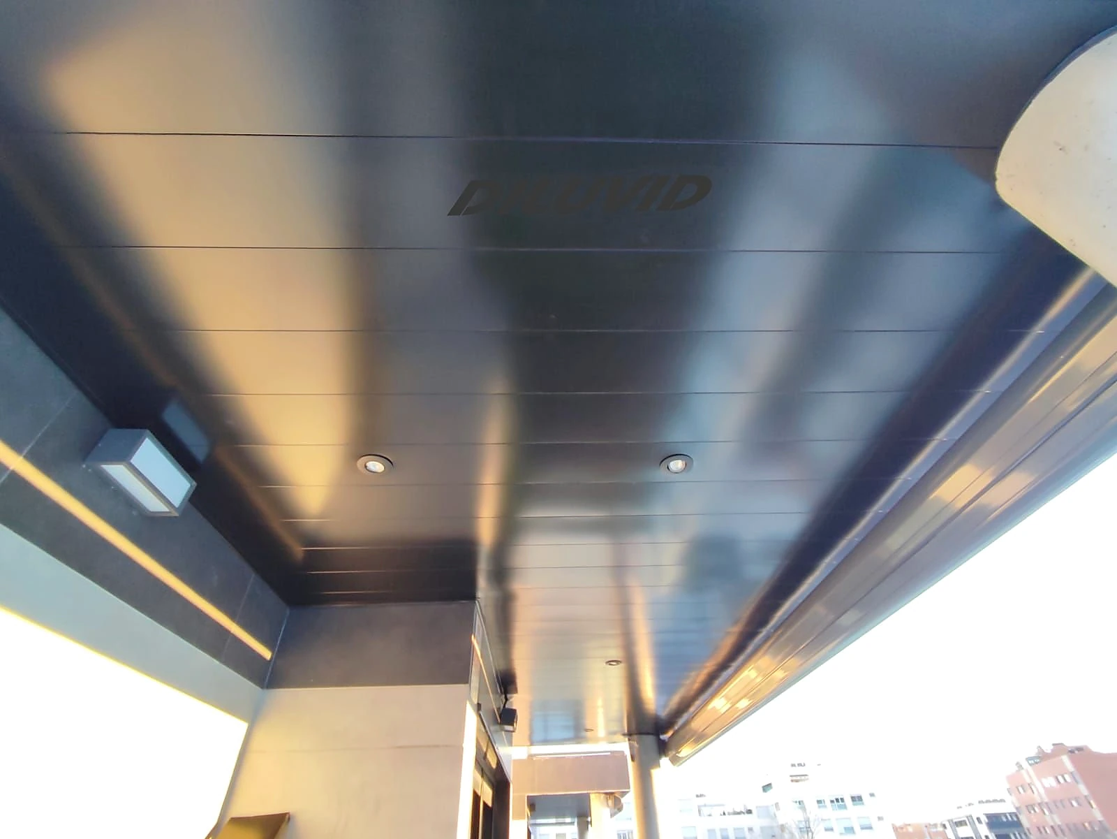 Techo de aluminio oscuro con iluminación integrada en balcón