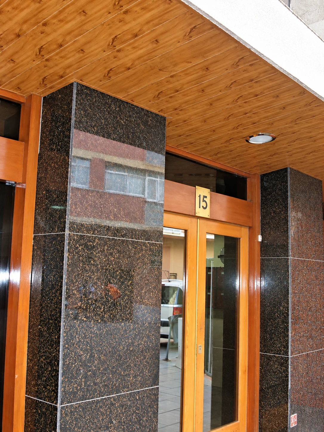 Techo de aluminio acabado madera en entrada de edificio